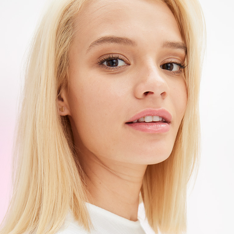 A female model wearing natural makeup looks into the camera.